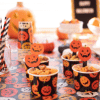 Halloween table cloth with close up of mini cups of nuts, paper straws, and other Halloween Party foods