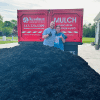 two people in front of mulch pile in front of Musselman Red Truck