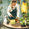 Women wearing white turtleneck and blue apron as she repots plants in outdoor shed