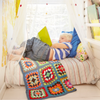 Little boy reading book in reading nook in window with colorful pillows and blankets