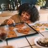 Woman icing Gingerbread house Woman leaning over baking tray icing unassembled pieces of Gingerbread house