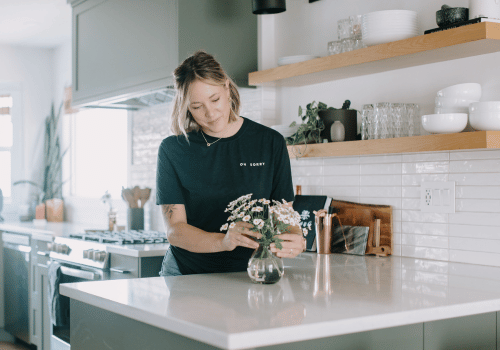 colleen pastoor arranging flowers in vase on white kitchen counter