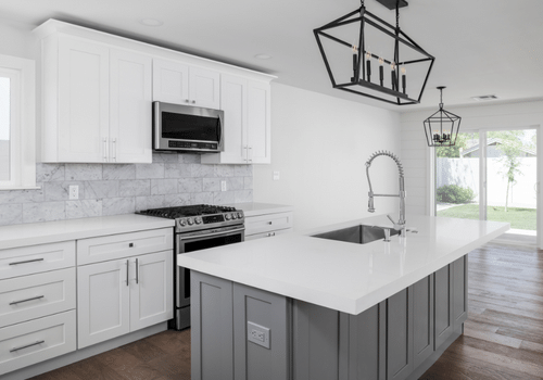 modern empty white kitchen with white marble island and hanging black metal light fixture and freshly painted white cabinets