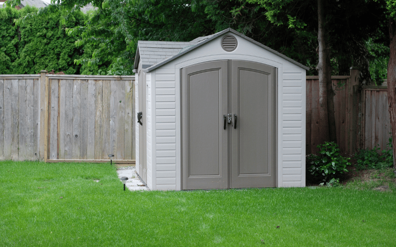 Backyard white and grey shed on bright green grass