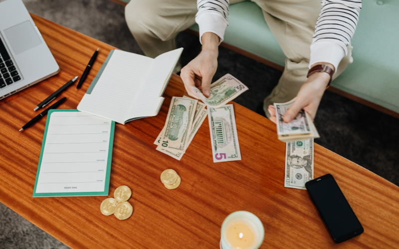 Woman counting American money beside budget sheet / ledger on hardwood table