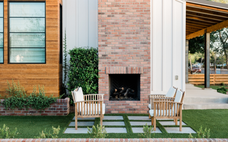 home exterior with two benches across from each other in front of fireplace embedded in brick