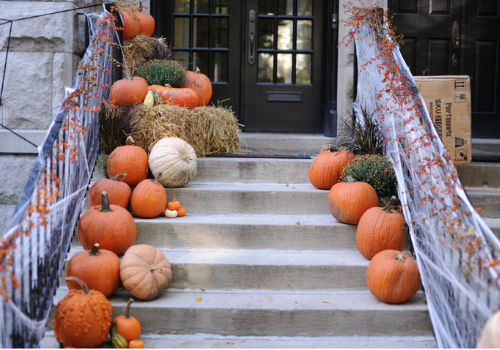 Pumpkins and cobwebs and hay on front porch steps 