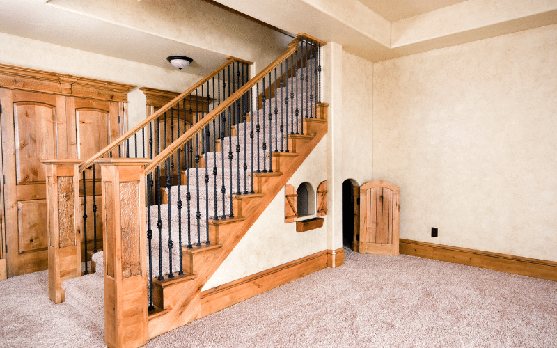 Hideaway under stairs in basement with rounded top wooden door and old fashioned windows. Kids play area