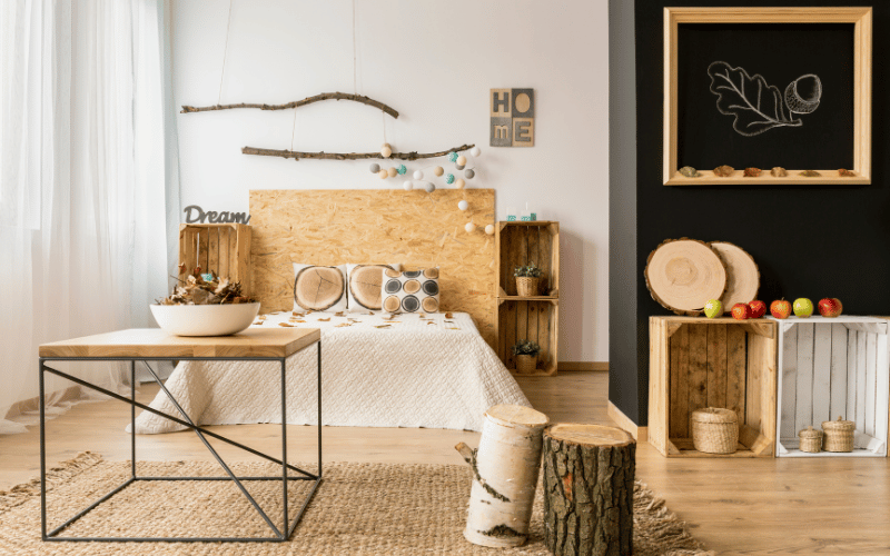 Open concept farmhouse nature inspired bedroom with black wall and chalk board, unfinished wooden headboard and tree stump decor with a