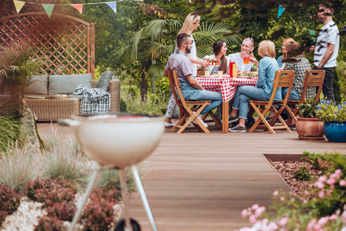 deck with bbq and group of friends eating a picnic