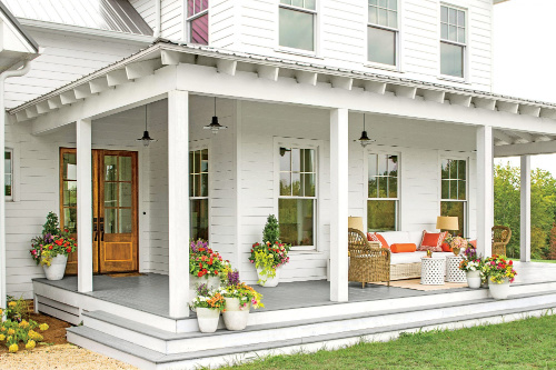 White two story house with colorful plants on front porch